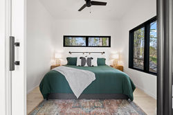 Lofty Ledges Hangout Primary Bedroom Suite with white walls and black window frames. There is a smal