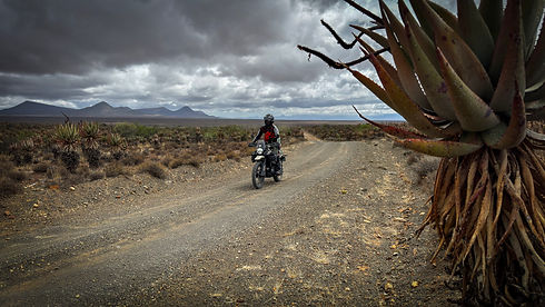 Adventure motorcycle riders descending a gravel mountain pass in the Karoo during the Karoo Wanderlust motorcycle tour from Graaff-Reinet to the Garden Route, South Africa
