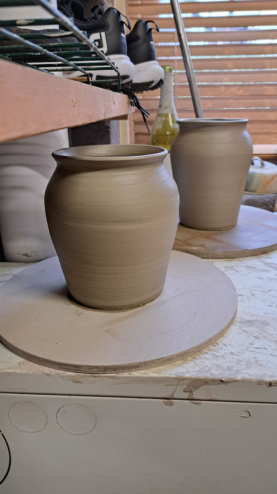 Two unfired clay mugs on wooden boards