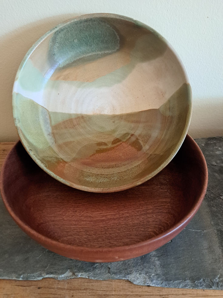 Ceramic bowl with earthy colours over a dark wood bowl handmade in Northumberland