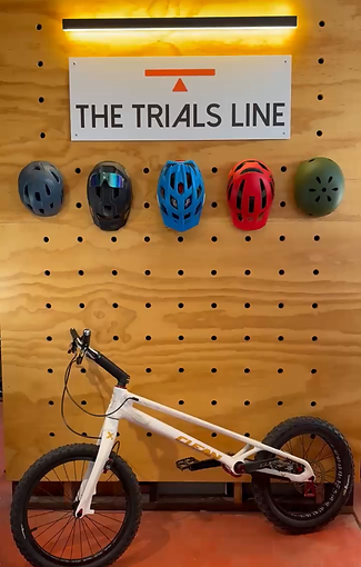 White Clean K1 trials bike in front of The Trials Line Logo
