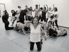 Foto 21: pessoas em pé e deitadas numa sala de ensaio, reunidas em pose para foto.