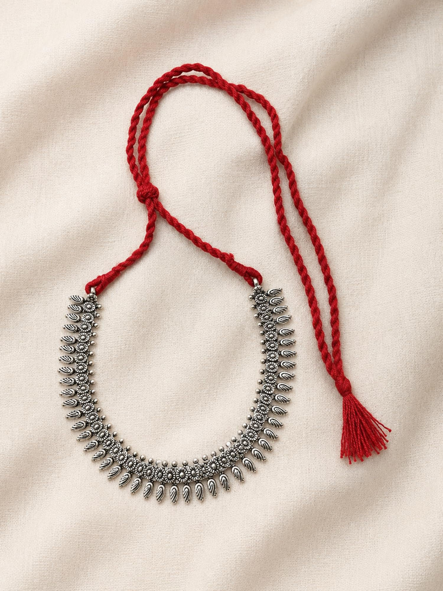 1. Athizay oxidised silver necklace with red thread and detailed teardrop charms, arranged on soft cream fabric.