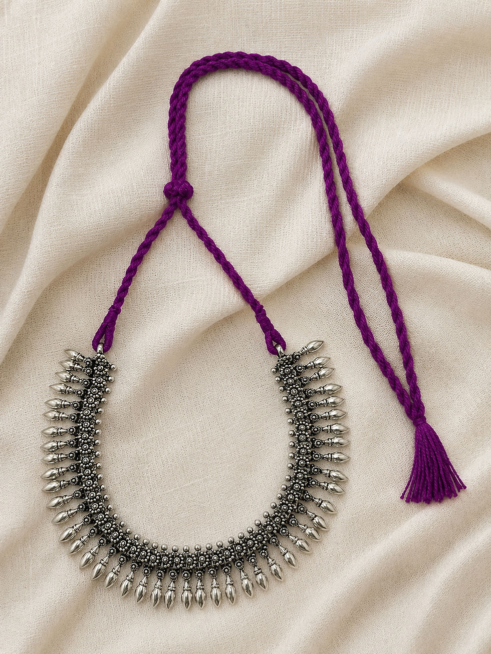 Purple thread Athizay oxidised silver necklace with intricate detailing and elegant teardrop charms on a soft fabric backgrou