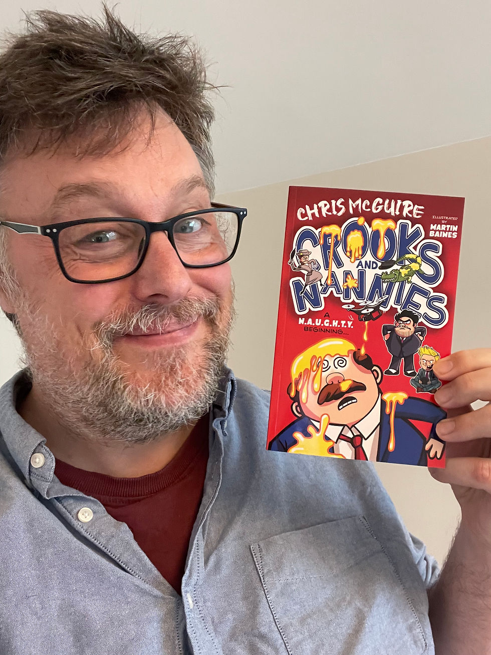 Author picture of Chris McGuire holding a copy of Crooks and Nannies