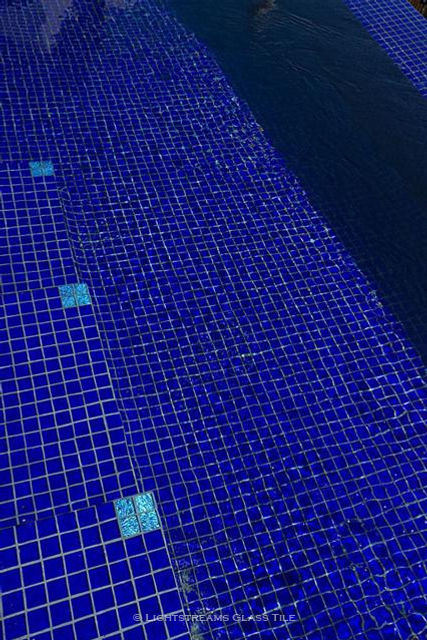 An all glass tile swimming pool of Lightstreams Renaissance Collection Royal Blue glass tiles, four Aegean Sea Jewel Glass Accent tiles create stunning medallions for the corners of the pool steps, resulting in beautiful and functional pool step markers. American Made Lightstreams Glass Tile Jewel Blue Tile which can be used as accent tile for pool tile, spa tile, waterline tile, floor tile, wall tile, step glass tile, step markers, fountain tile, kitchen tile, backsplash tile, shower tile, bathroom tile, and spillway tile