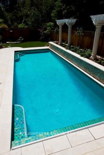 American Made Lightstreams Glass Tile Renaissance Collection Celadon green tile is used on the step of this pool as pool tile, step marker tile, and waterline tile. This photo really shows off the iridescent tile side and the smooth shiny side of Lightstreams signature reversible tile