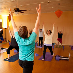 Yoga instructor leads a class in arm-raised pose