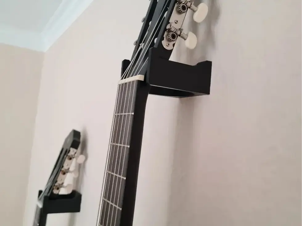 Manico e paletta di chitarra acustica nera appesi al muro bianco.