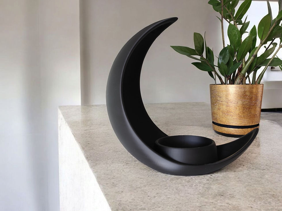 Miniatura: Portacandele nero a forma di luna crescente su tavolo con pianta.
