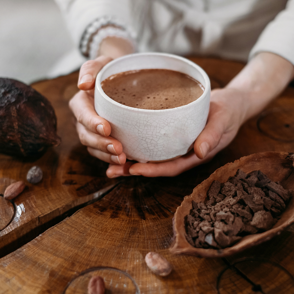 a woman holding a white cup filled with warm cacao drink surrounded by cacao beans