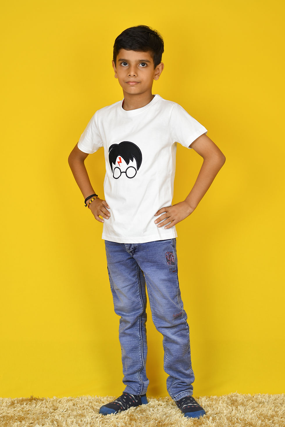 Thumbnail: a front view photo of a boy sitting and wearing a t shirt by Hugs&Hues having Harry Potter appliqué embroidered on it and posing