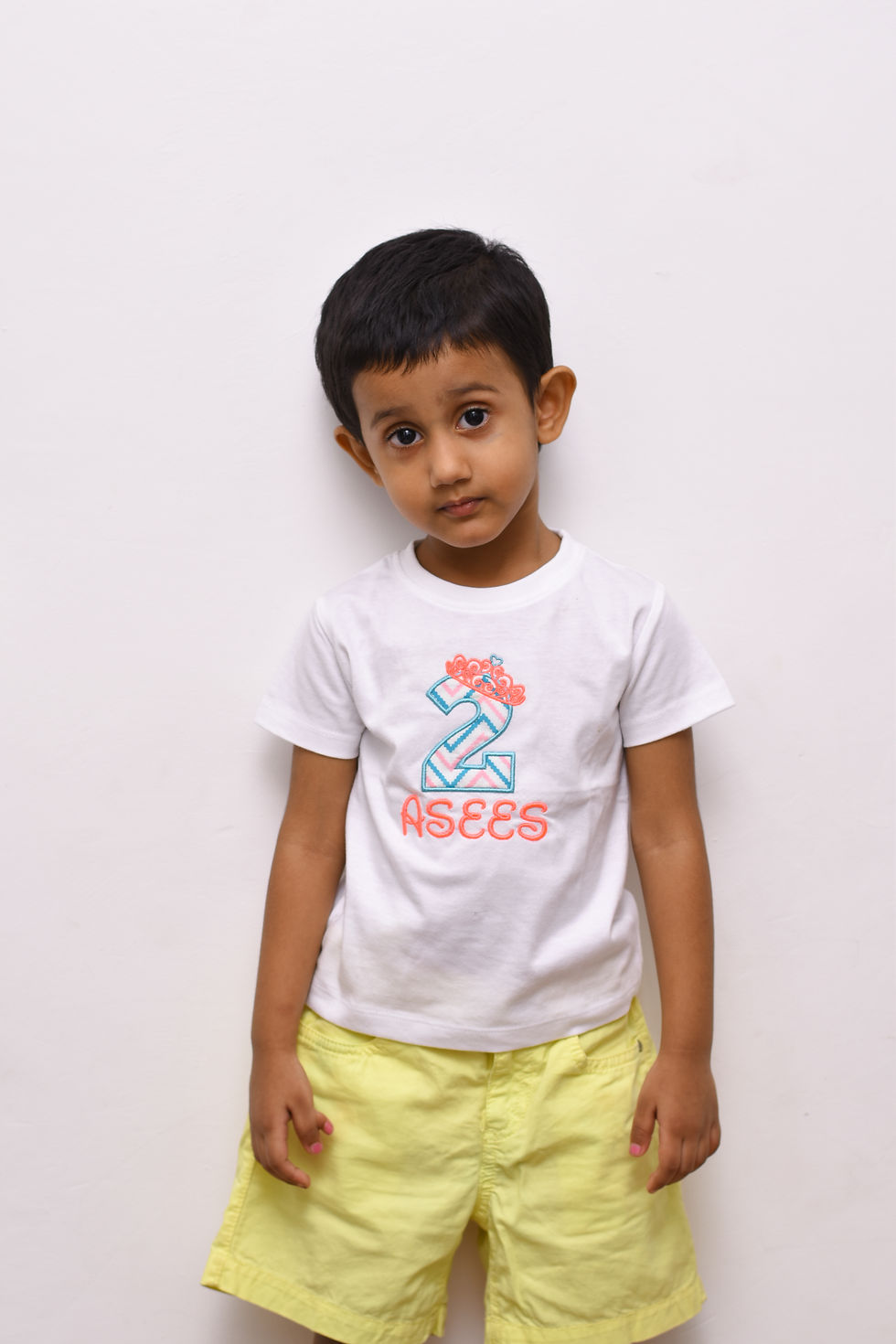 a photo of a boy wearing t shirt by Hugs&Hues having number 2, a name and a tiara/crown embroidered on it