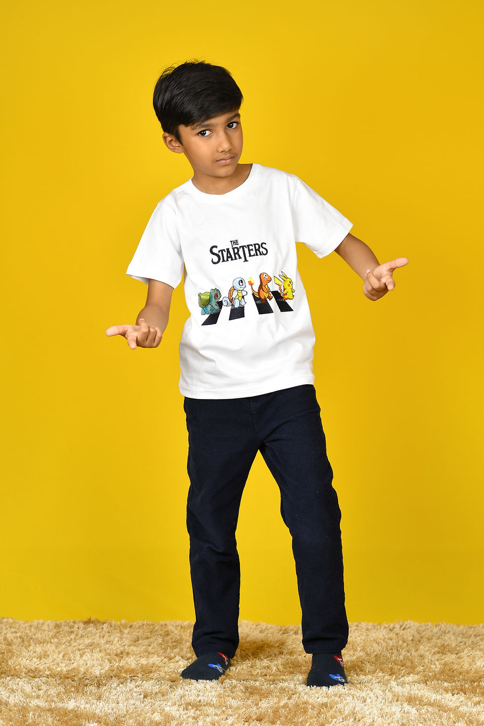 Thumbnail: a photo of a boy standing wearing a t shirt from Hugs&Hues having pokemons crossing a road and "the starters" embroidered on it and posing