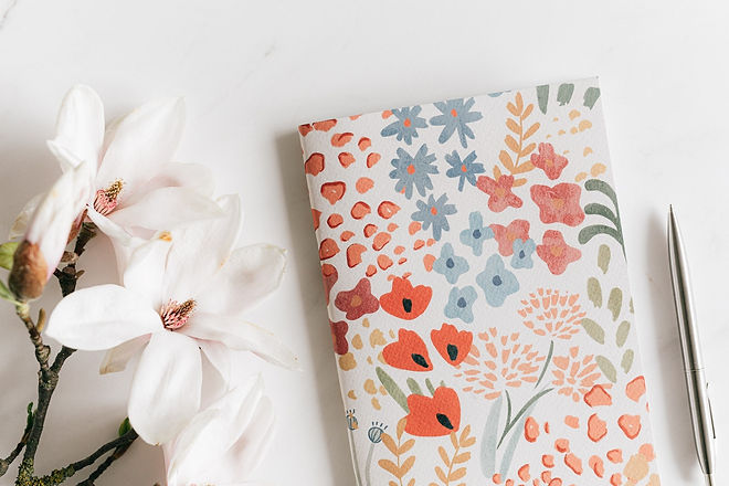 White flowers, pen and notebook on a desk