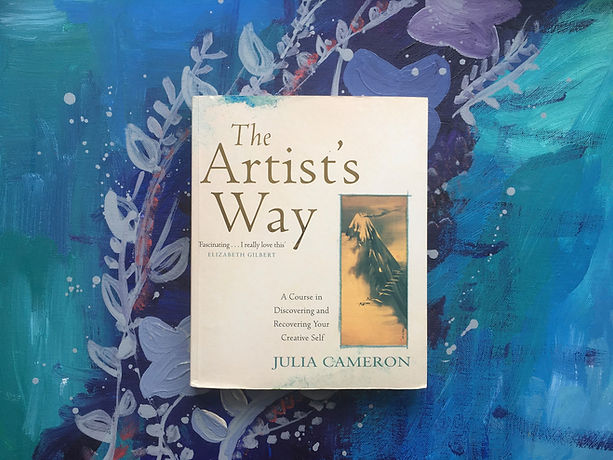 The book "The Artist's Way" with blue painting in background