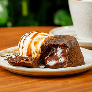 Petit gâteau de chocolate servido com sorvete e cobertura cremosa.