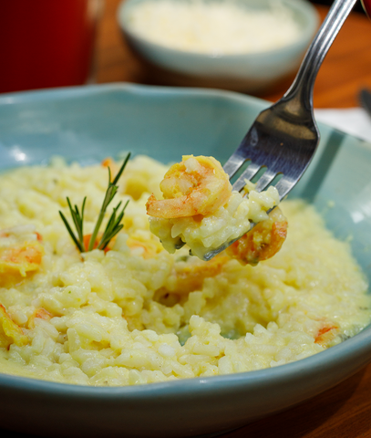 Arroz cremoso servido em prato fundo com ervas frescas.