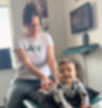 Baby Eva smiles as she lies on her stomach while Dr. Tara applies a gentle adjustment in her low back