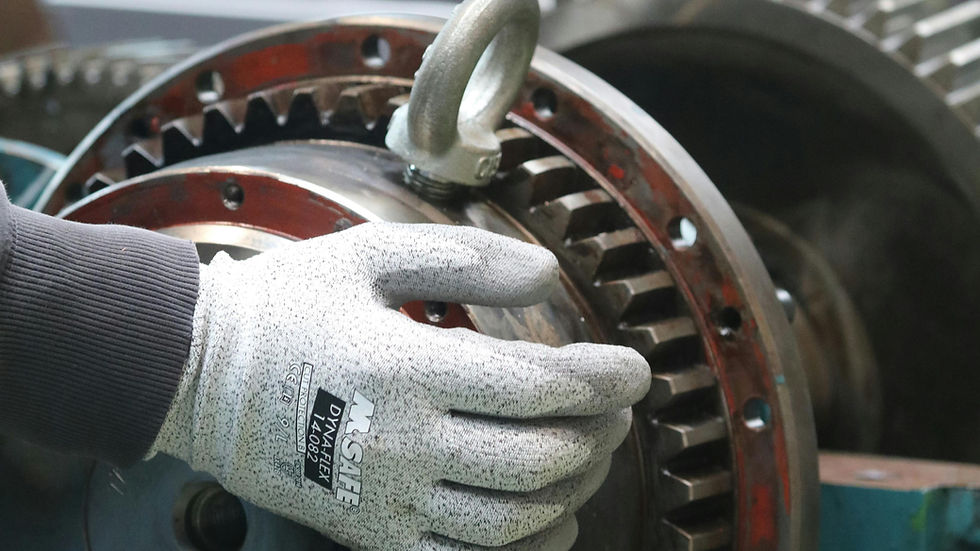 A gloved hand grips a large metal gear with a red rim. Immediately show industrial grinding, maintenance reality