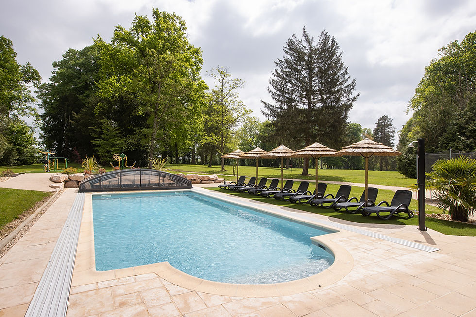 Outdoor pool with lounge chairs and straw parasols at Château de Montsymond