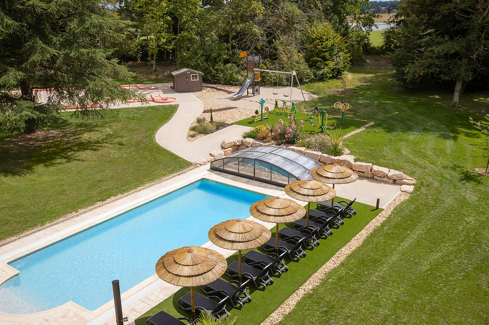 Outdoor pool with lounge chairs and playground in the background viewed from above.
