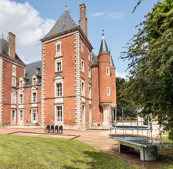 Red brick south-eastern corner of Château de Montsymond under a blue sky