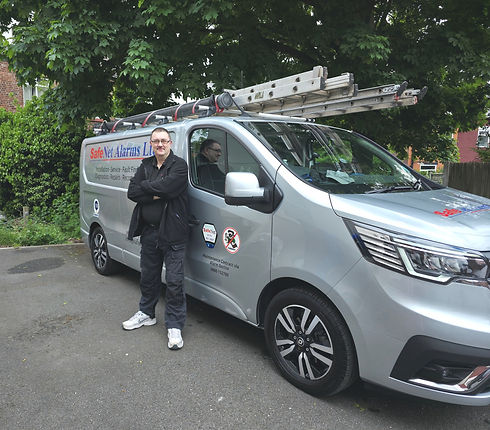 A man stands beside a van with a ladder secured on top, ready for work or a project