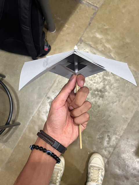 Hand holding a folded paper prototype, showing quick form exploration, ergonomics testing, and early product concept refinement.