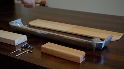 Close-up of wooden blocks and parts on a desk, showing material exploration and form development for a product prototype.