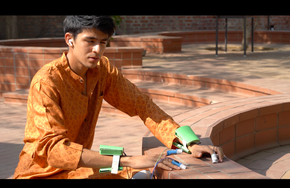 a young man wearing an orange shirt is using a green device on his wrist