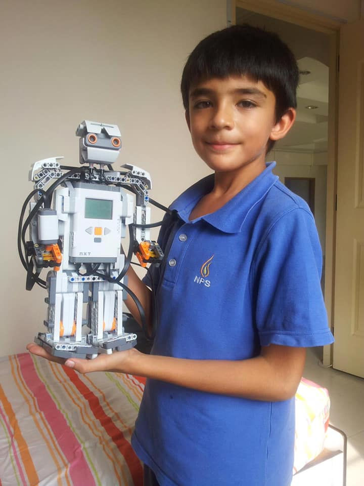 Young boy proudly holding LEGO robot creation; Ansh Trivedi Design.