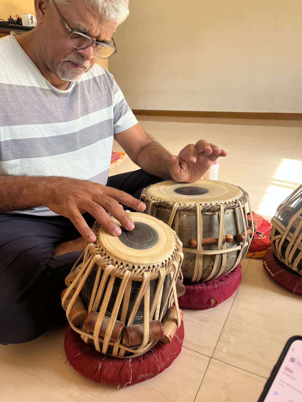 a man sits on the floor playing a drum