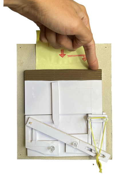 Hand holding a foam-board mechanism prototype, showing physical interface experimentation, motion studies, and rapid prototyping.