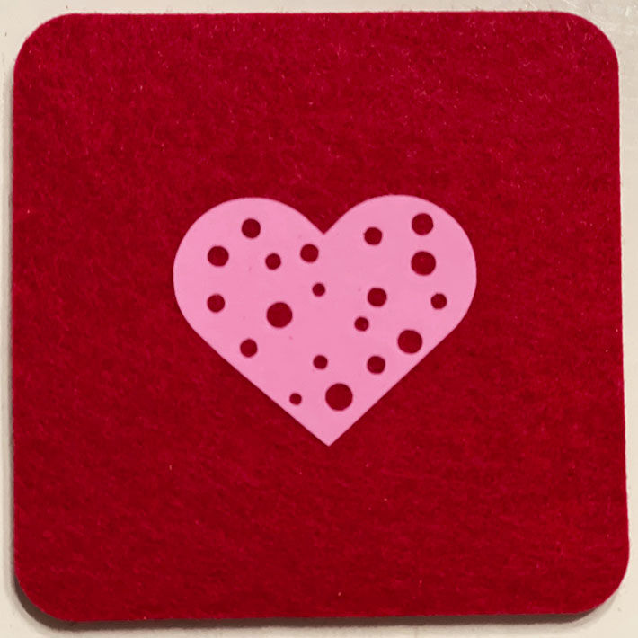 Thumbnail: Closeup image of red wool drink coaster with a polka dot pink heart design heat transfer