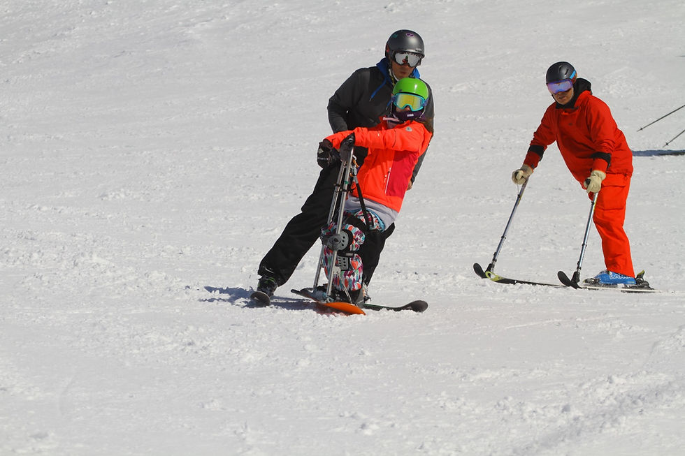 Esquiador en sit-ski con guía y otro esquiador. Esqui adaptado.
