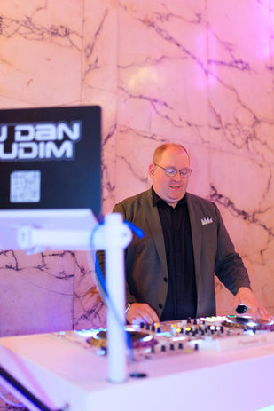 DJ Dan Fudim, the Best DJ in NYC, performing live at a vibrant corporate event with a professional DJ setup and colorful lighting.
