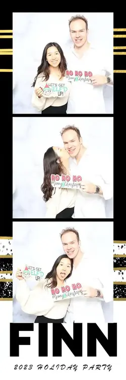 Couple at the FINN 2023 Holiday Party enjoying a festive photo booth session with holiday props, whi