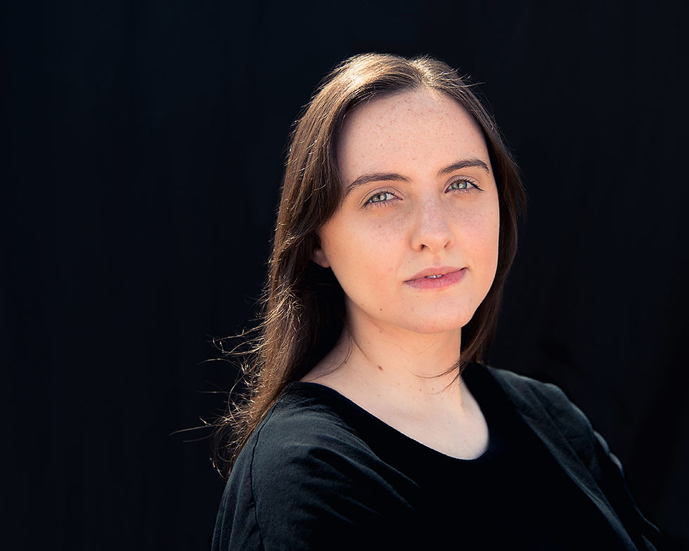 A strong clean headshot of a striking young woman on a black backdrop.