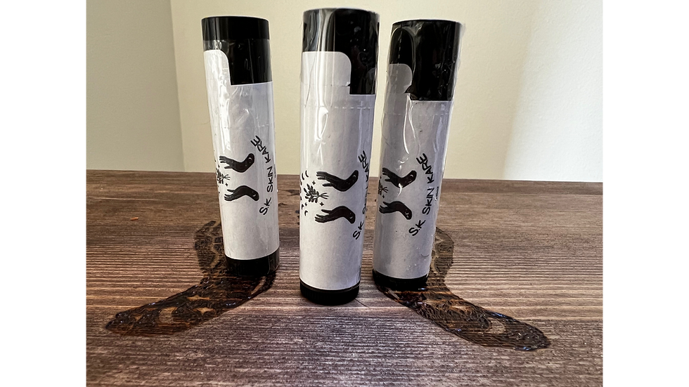 Three skincare lip balm tubes labeled S.K. Skin Kare on wood surface. Background is plain and light-colored.