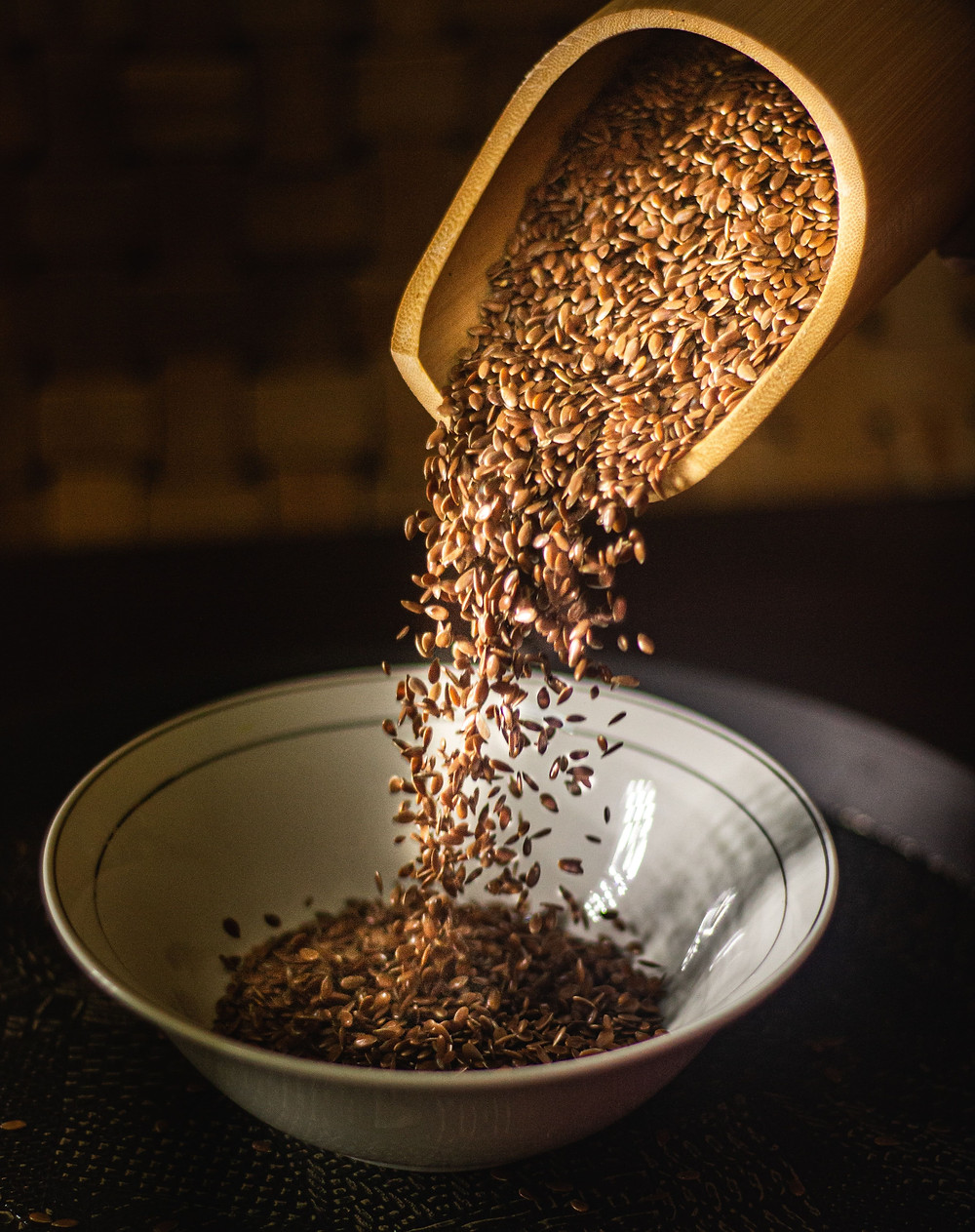 Somebody putting flax seeds into a bowl.