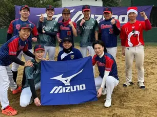10人の男性が野球グランドで笑顔で集合写真を撮っている