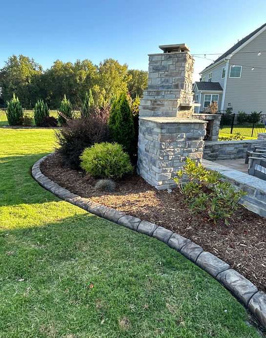 Natural stone curbing beautifully frames this outdoor patio and landscape