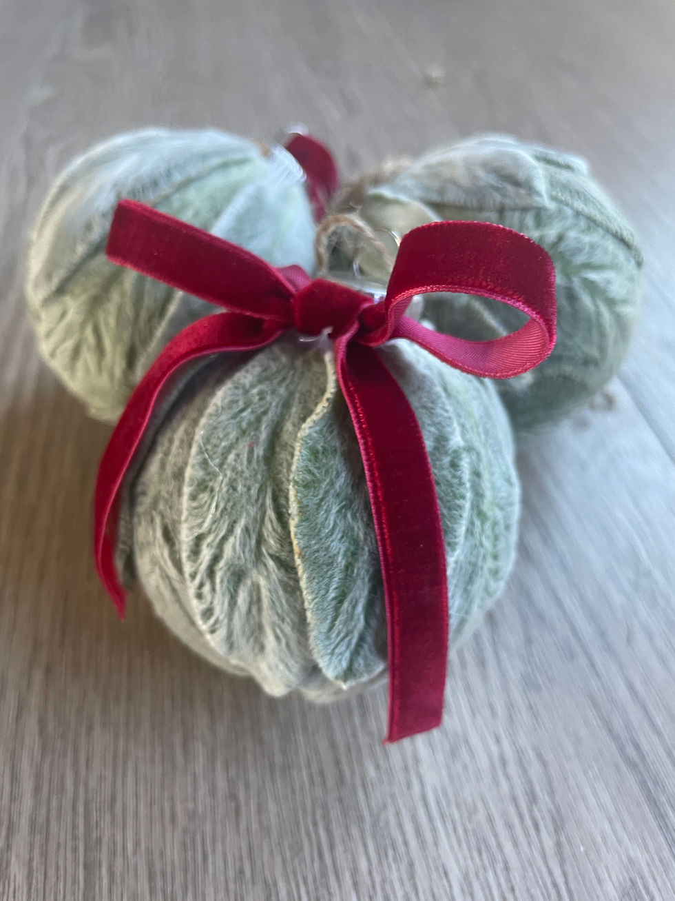Three ornaments with a red ribbon on a wooden surface.