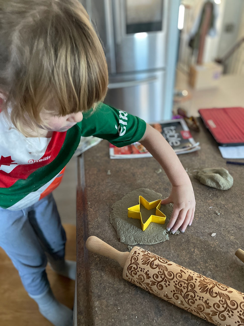 A child using a star-shaped cookie cutter to cut out some salt dough.