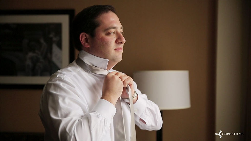 groom ties his neck tie for wedding