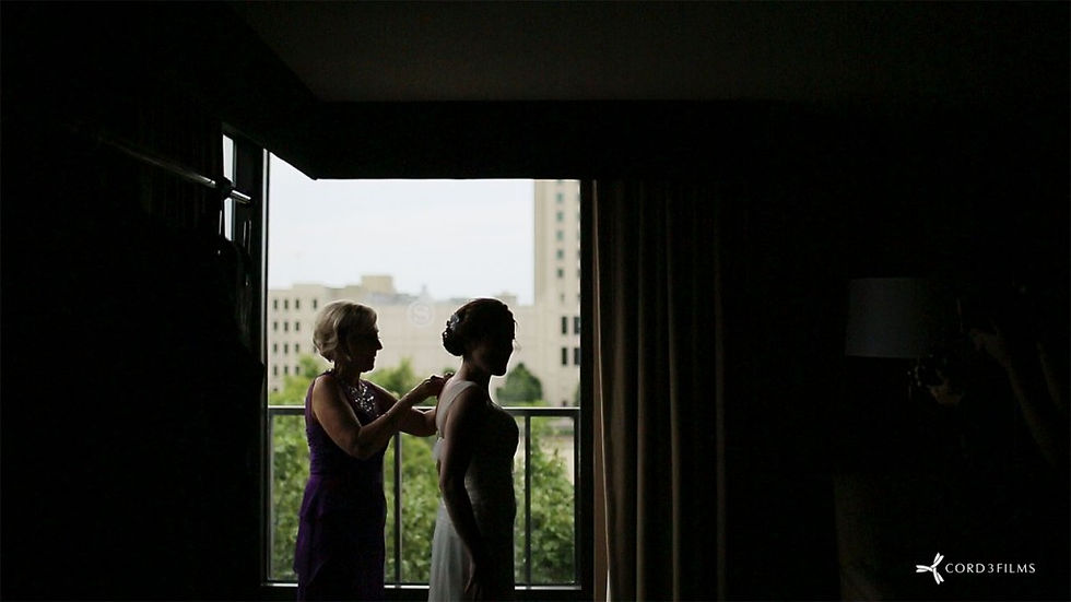 brides mother helps her fasten dress