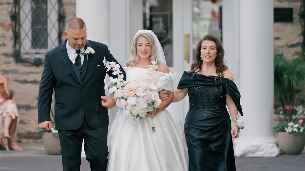 bride walks down the aisle outdoors with her parents
