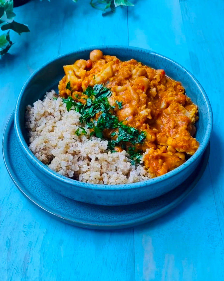 Bowl azul con Tikka Masala con hierbas sobre mesa azul; imagen apetecible y colorida, sin texto visible.