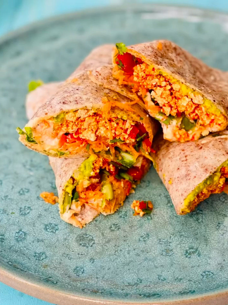 Trozos de wrap relleno con verduras y queso sobre un plato azul; colores vivos y aspecto apetitoso.